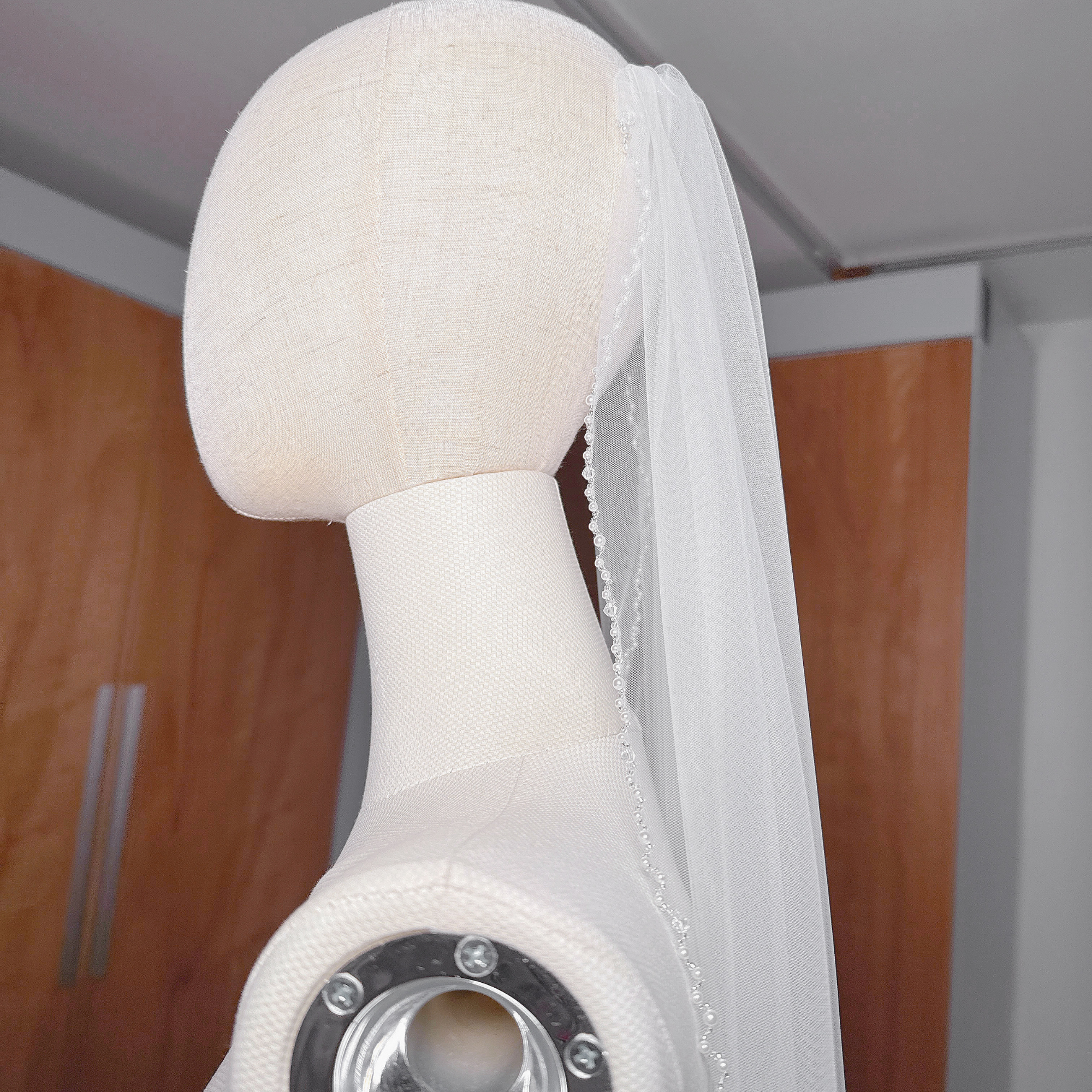 The cascading silhouette of an angel cut pearl trim wedding veil at cathedral length.