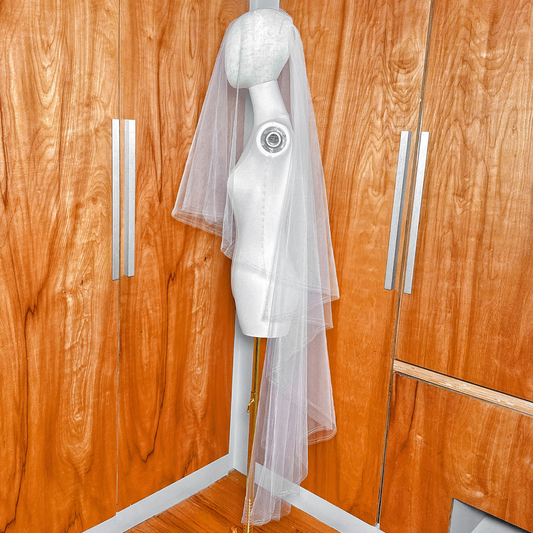 Angled shot of a waltz length two tier veil on a mannequin showcasing the silver metallic finish and tiered blusher style.