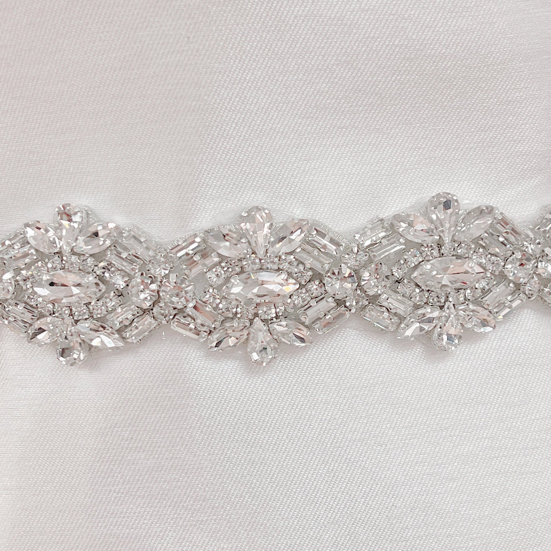 Close-up of an Art Deco beaded bridal belt featuring intricate geometric pearl and rhinestone patterns on a bridal mannequin.