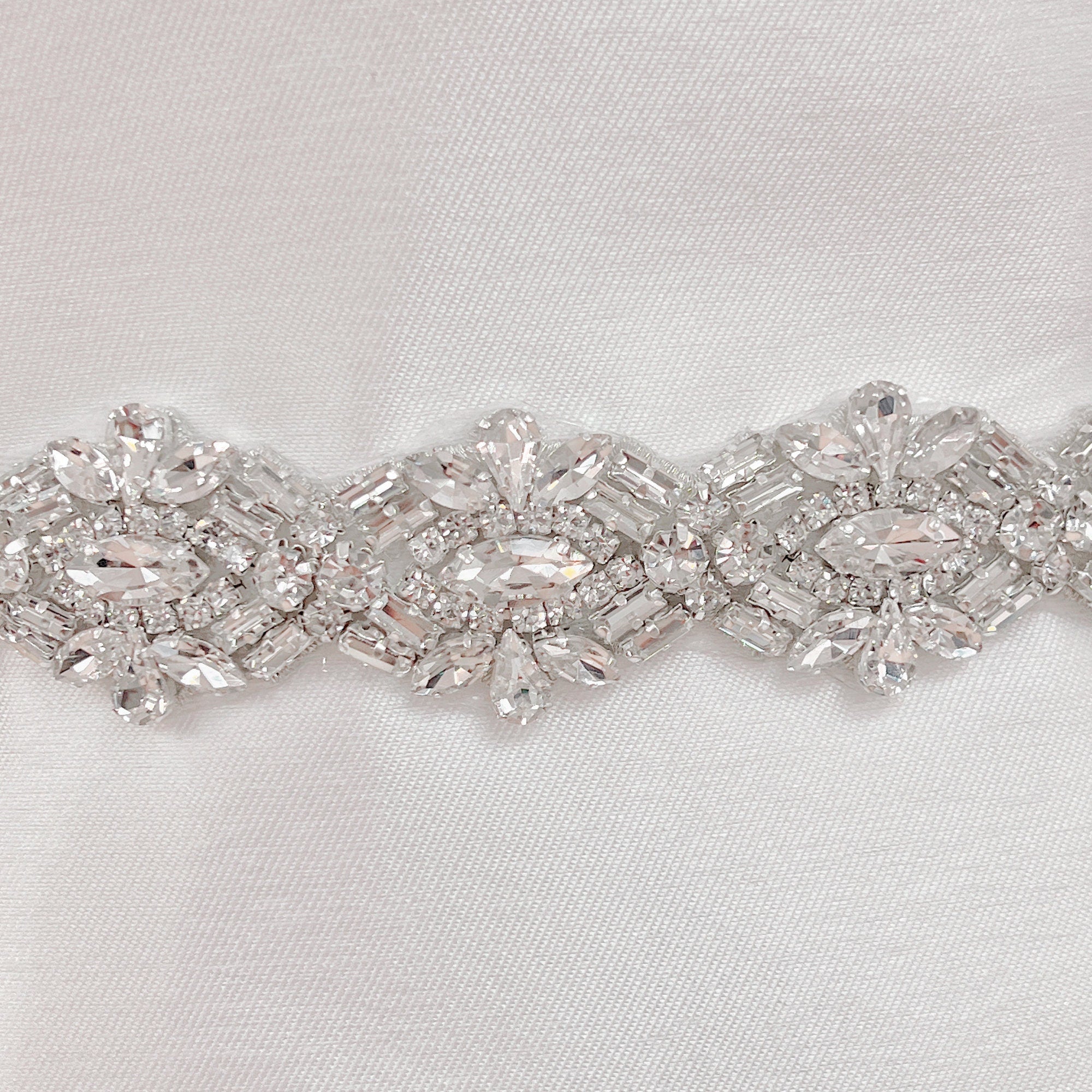 Close-up of an Art Deco beaded bridal belt featuring intricate geometric pearl and rhinestone patterns on a bridal mannequin.