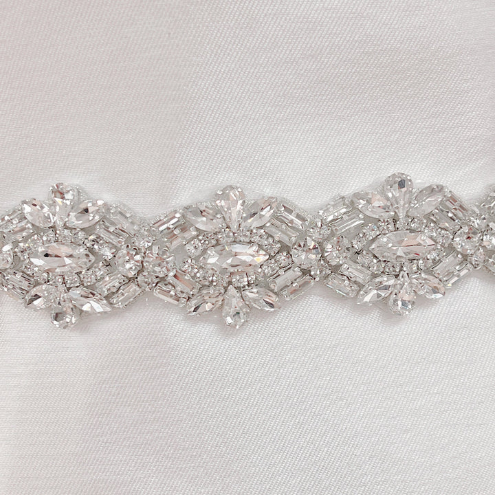 Close-up of an Art Deco beaded bridal belt featuring intricate geometric pearl and rhinestone patterns on a bridal mannequin.