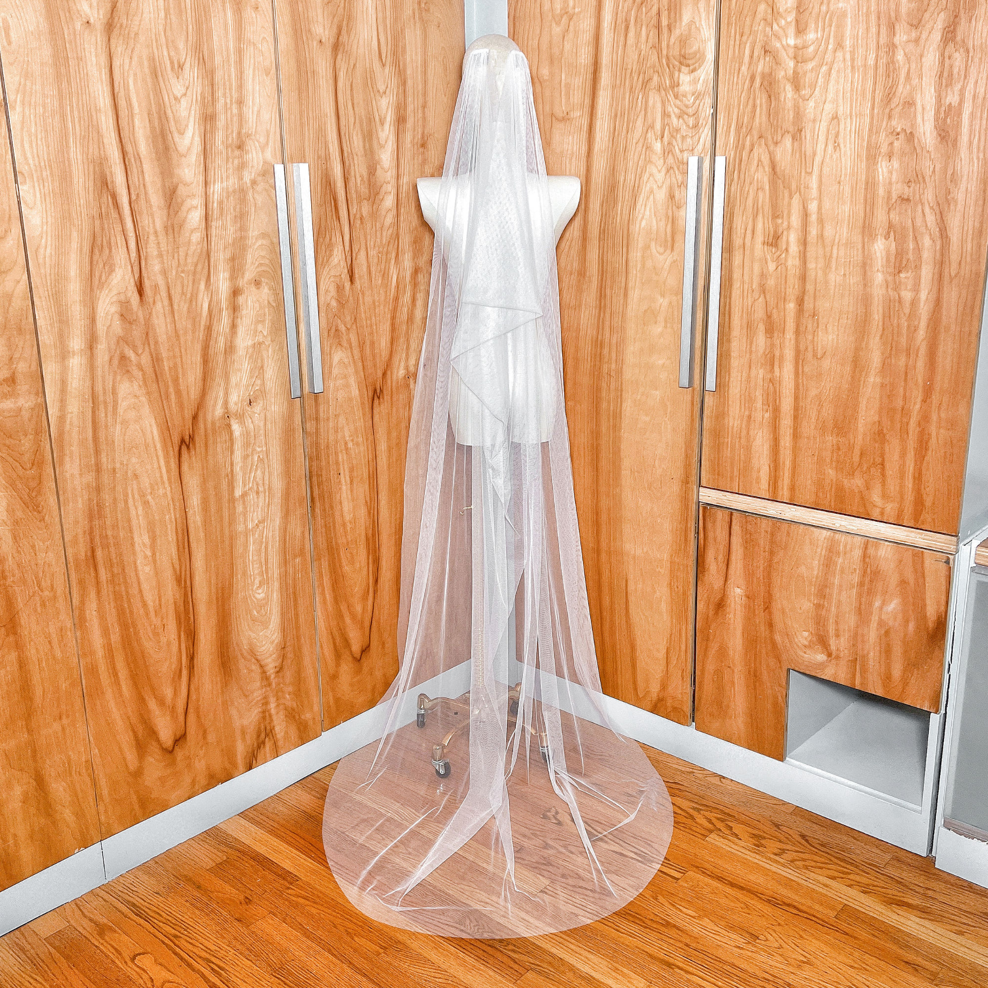 Rear view of a boho draped wedding veil cascading down in a classic cowl shape.