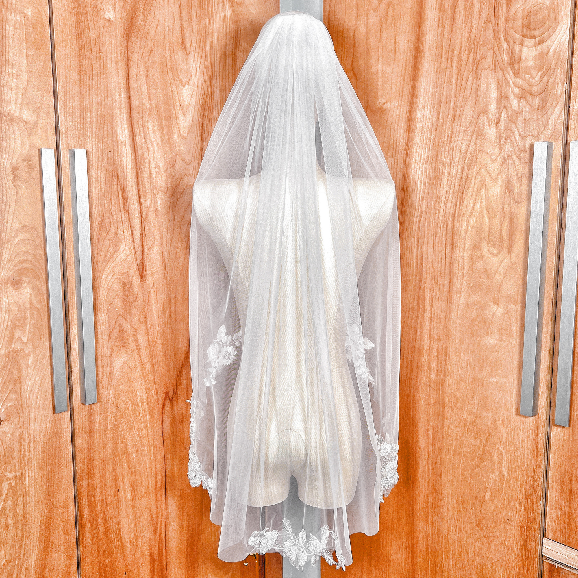 Back view of a single-tier fingertip length floral beaded lace wedding veil on a mannequin.