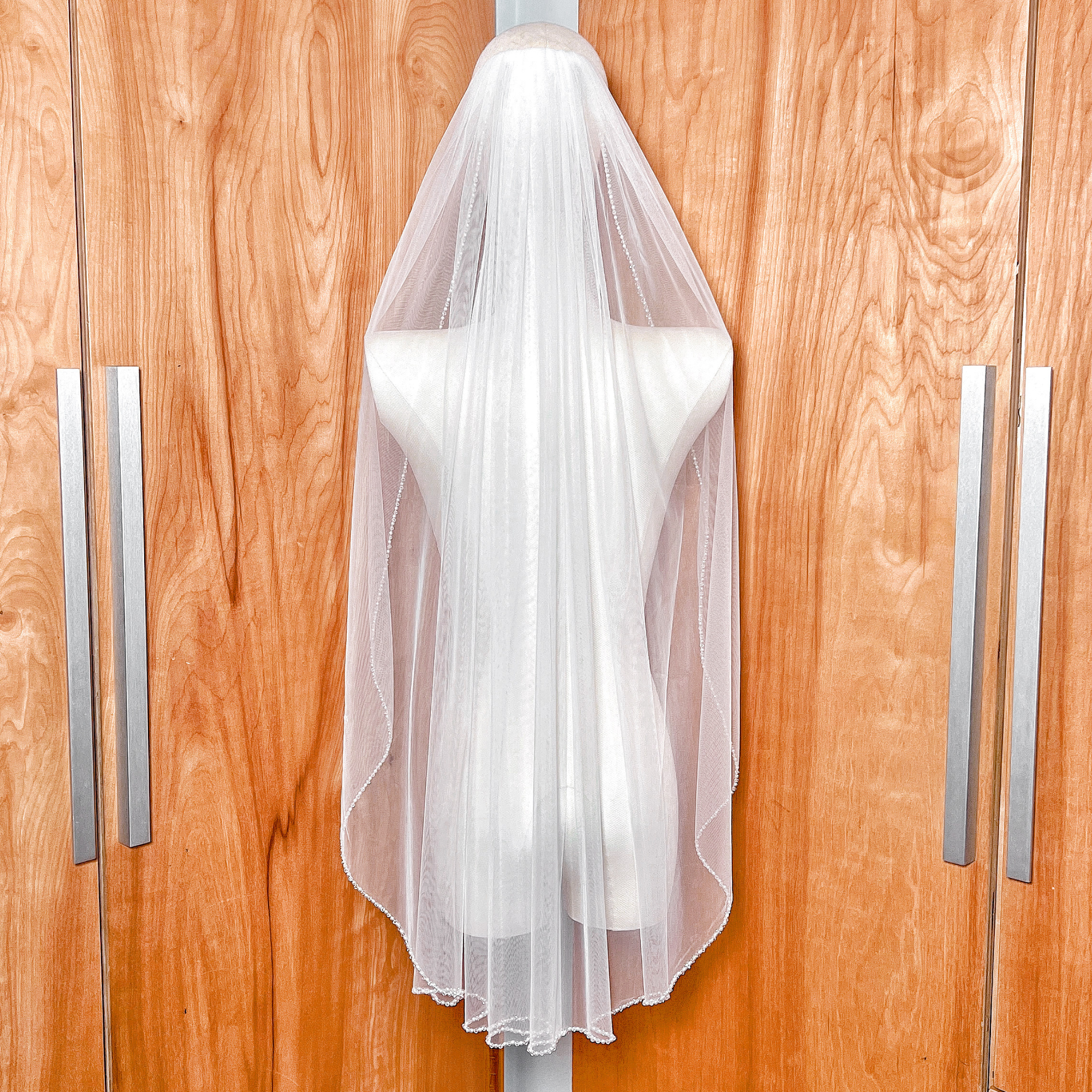 Back view of a fingertip length wedding veil illustrating how the pearl and crystal beaded edge drapes elegantly.
