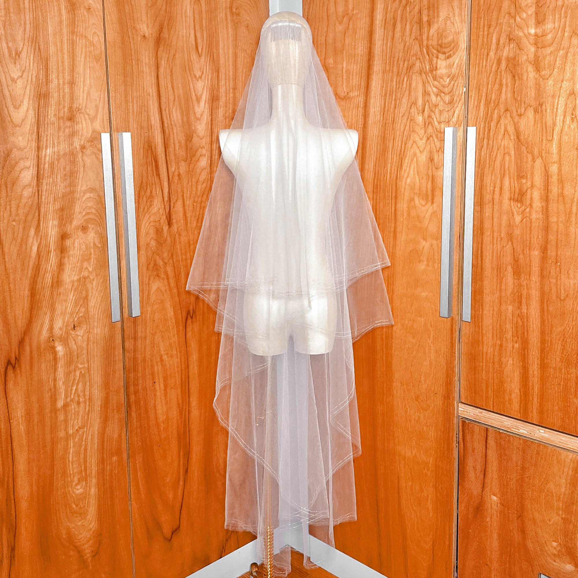 Back view of a waltz length two tier wedding veil on a mannequin highlighting the silver metallic trim and 60-inch length.