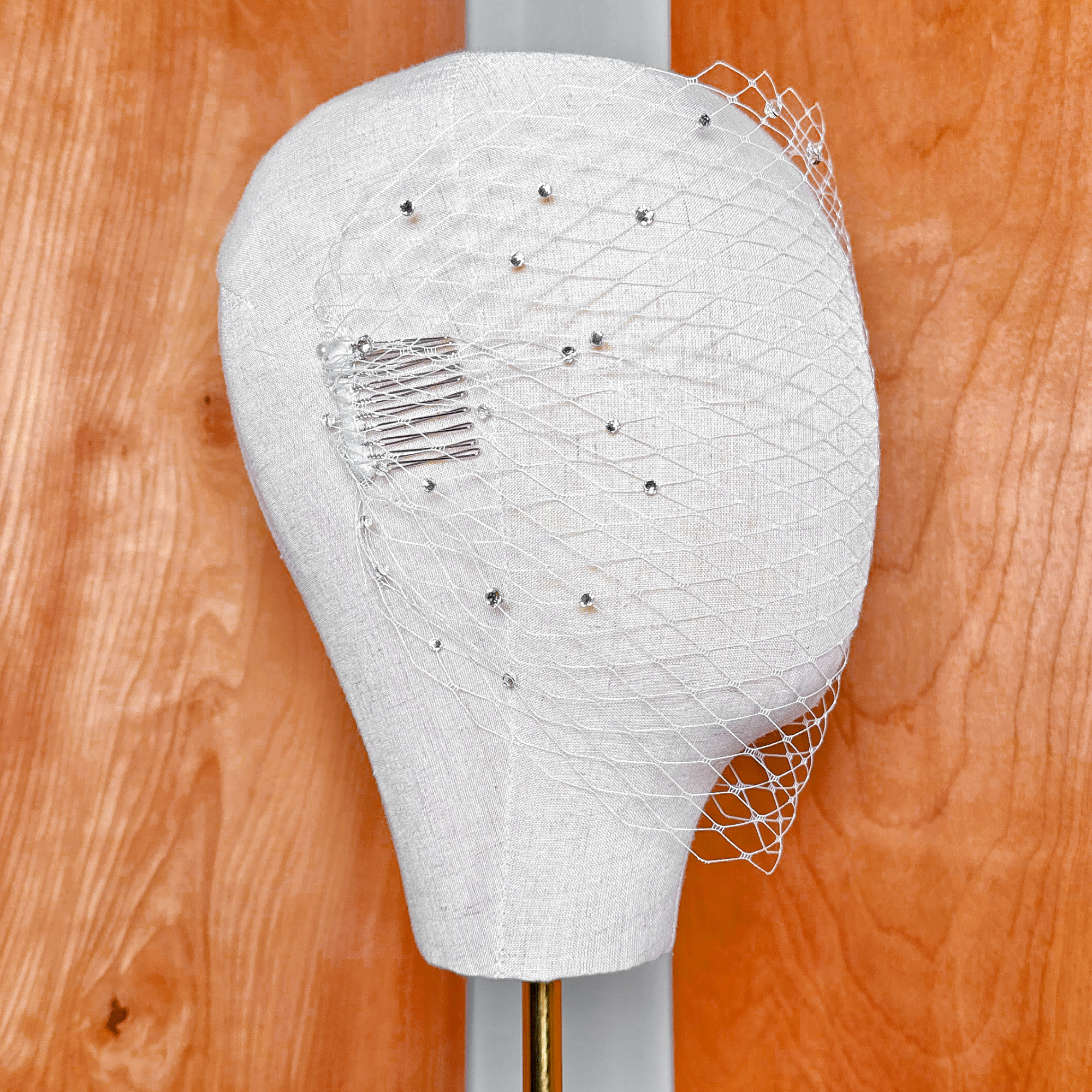 Detailed texture of a French net bandeau birdcage wedding veil with rhinestone accents.