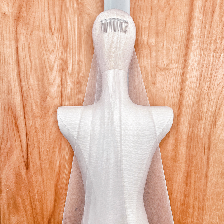 Close-up of the delicate raw edge on a barely there fingertip wedding veil, showing the high-quality, fine bridal mesh.
