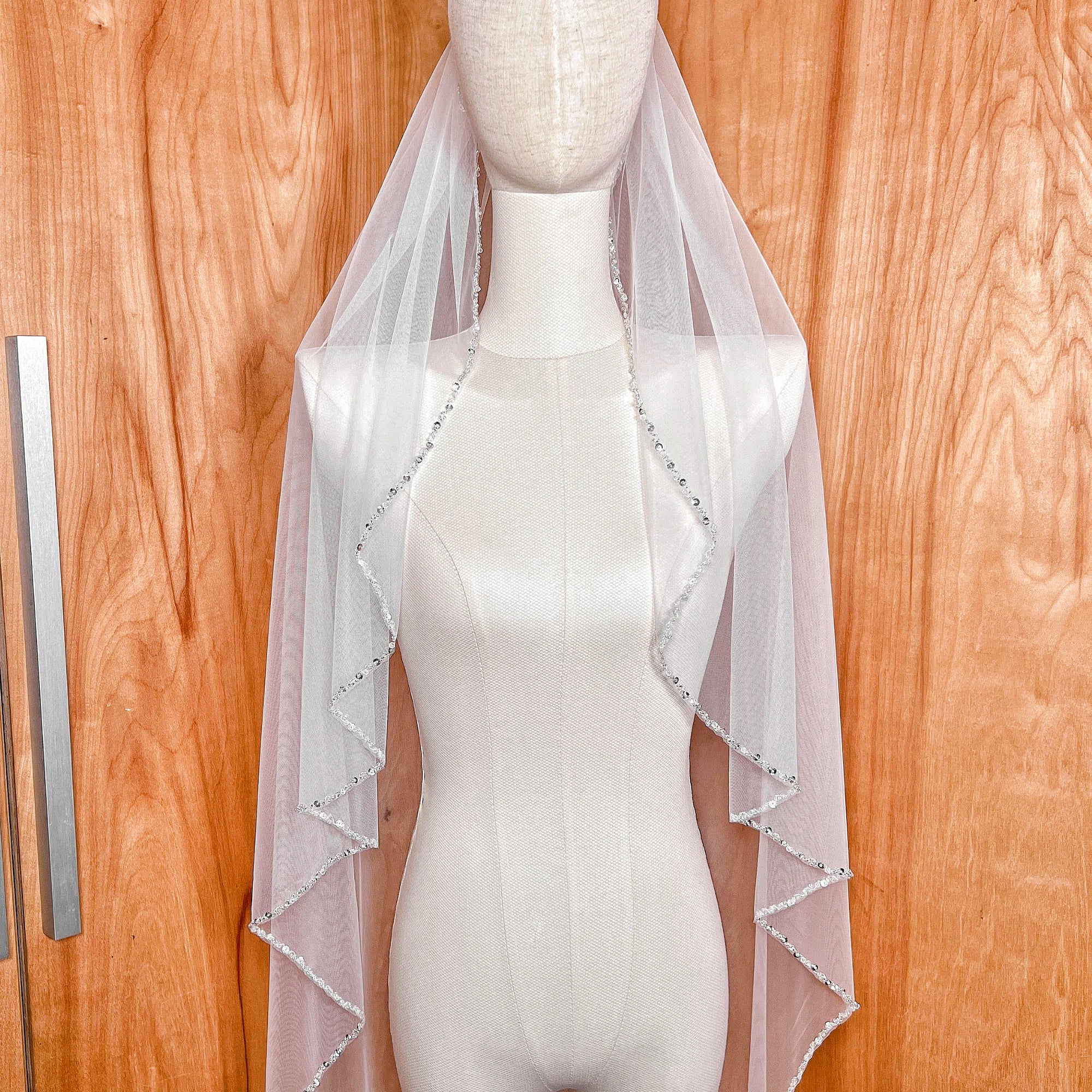 Side profile of a waltz length bridal veil featuring a shimmering beaded edge design.