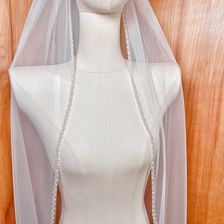 Close-up of the delicate beadwork on the edge of a soft tulle wedding veil.