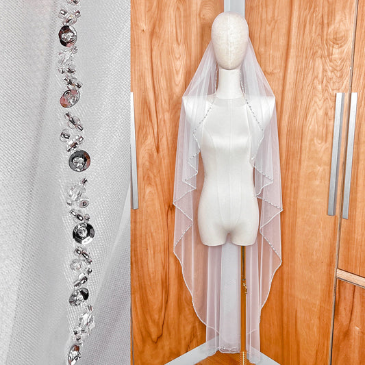 Front view of a waltz length beaded edge wedding veil with intricate silver bead detailing along the border.