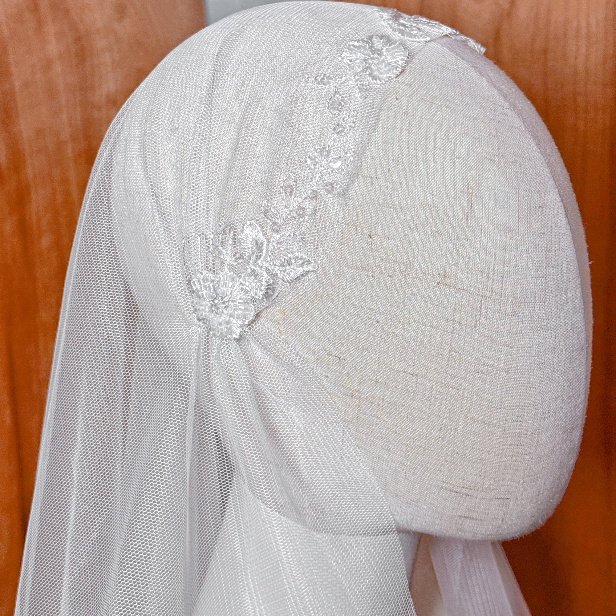 Close-up of the beaded lace cap on a vintage style Juliet cap veil showing hand-stitched beadwork on a mannequin head.