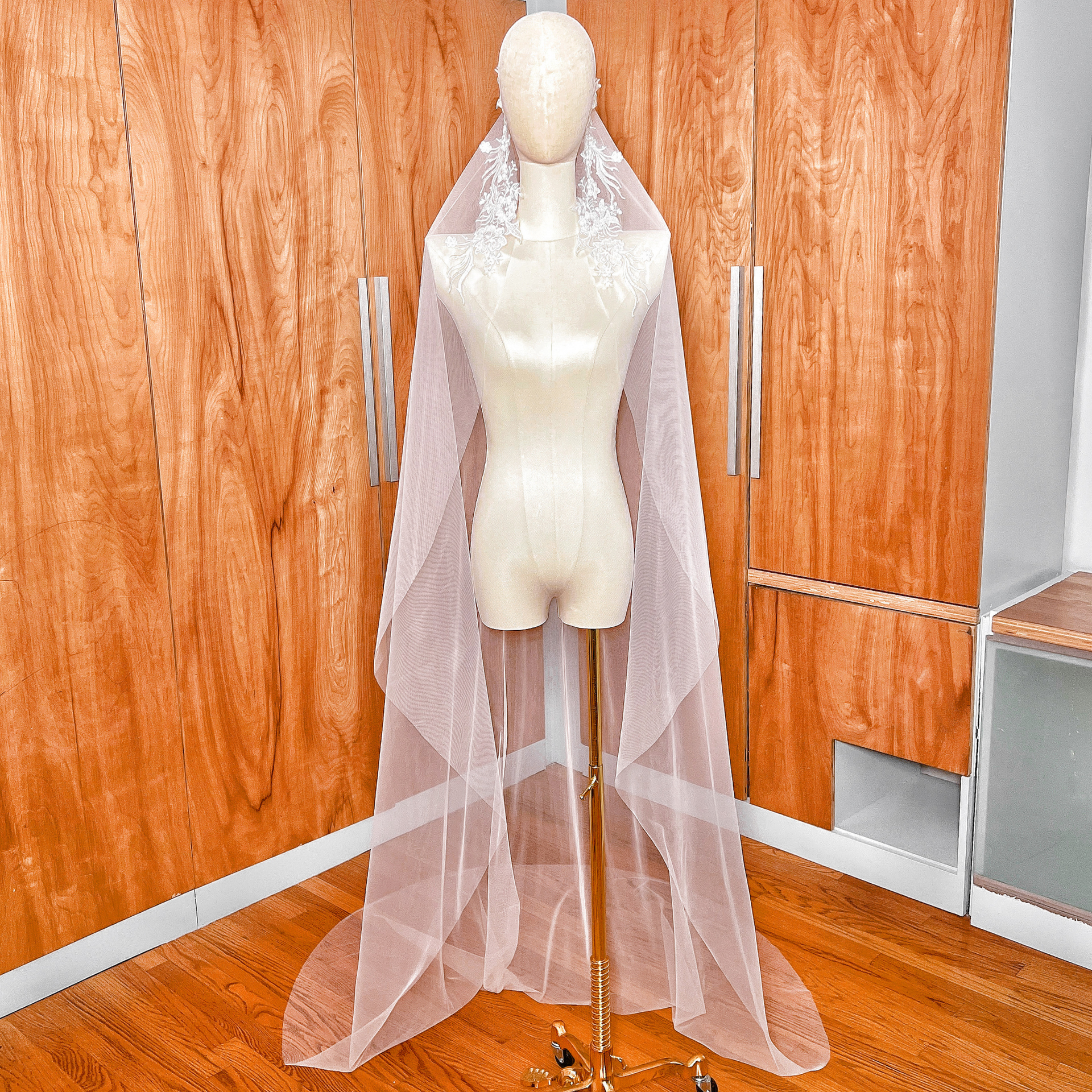 Front view of a beaded lace mantilla wedding veil in cathedral length draped over a mannequin, featuring intricate floral lace framing the face.