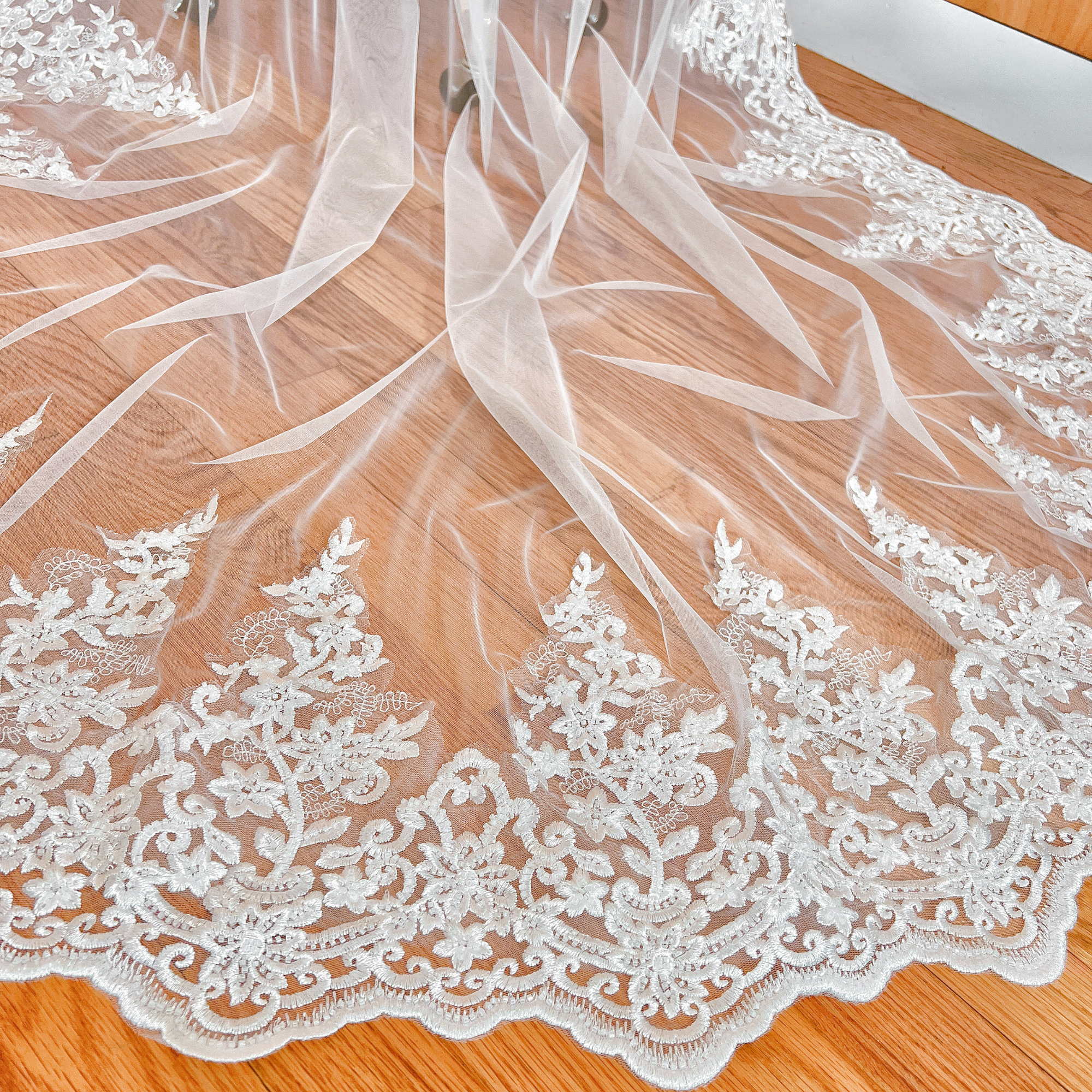 Close-up of the intricate hand-stitched beadwork and floral lace trim on a white chapel length wedding veil.