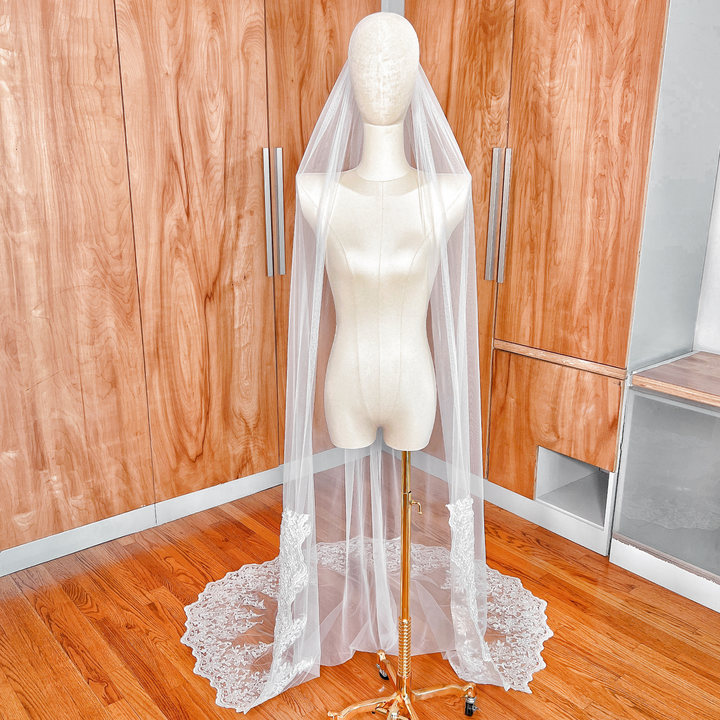 Front view of a chapel length beaded lace wedding veil draped elegantly over a bridal mannequin to show full floor-length detail.