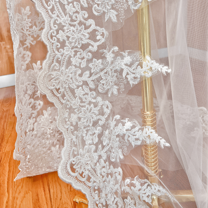 Side profile of a chapel length beaded lace wedding veil on a mannequin, showcasing the soft drape and delicate lace edges.