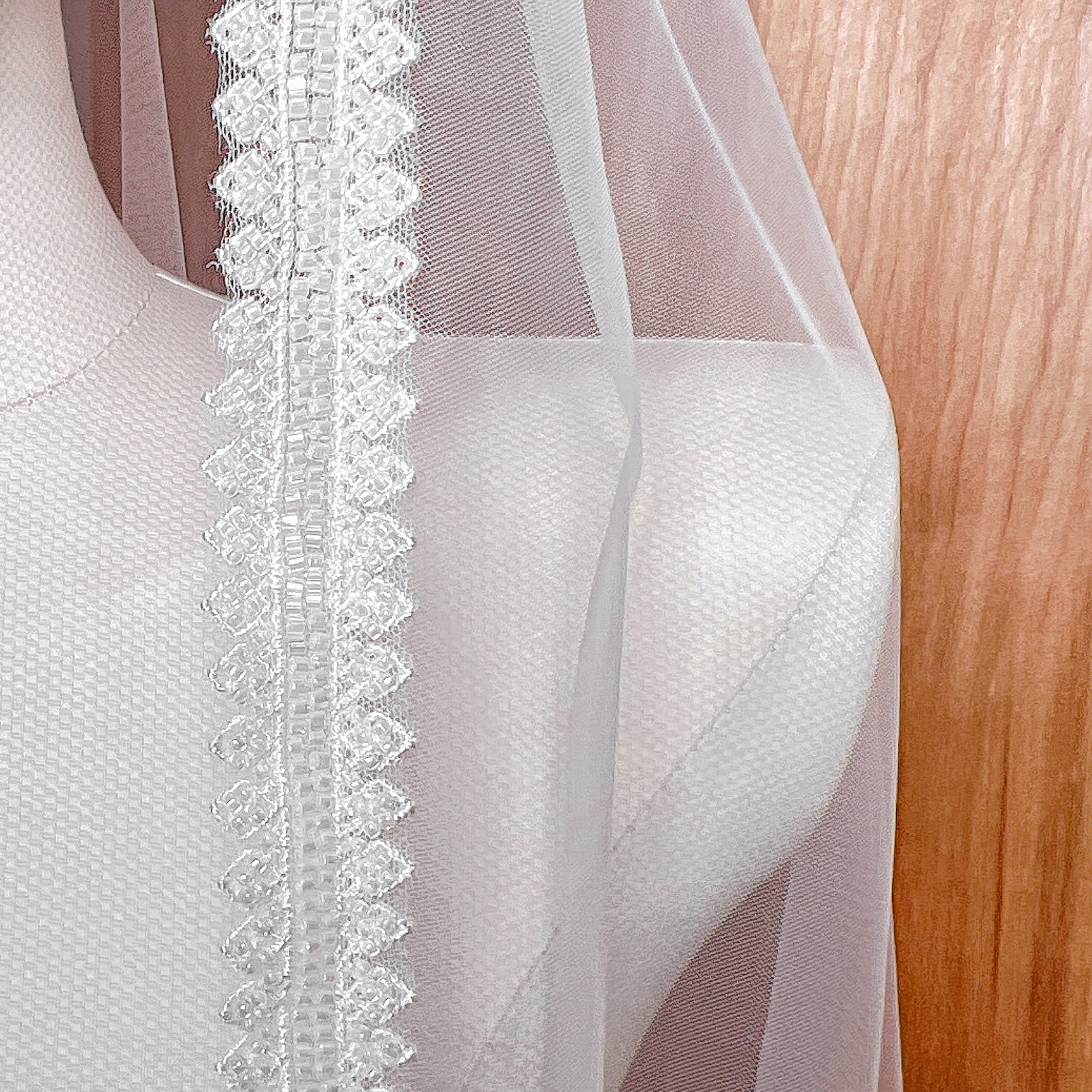 Close-up detail of the intricate hand-sewn beads and sequins on the edge of the beaded mantilla wedding veil.