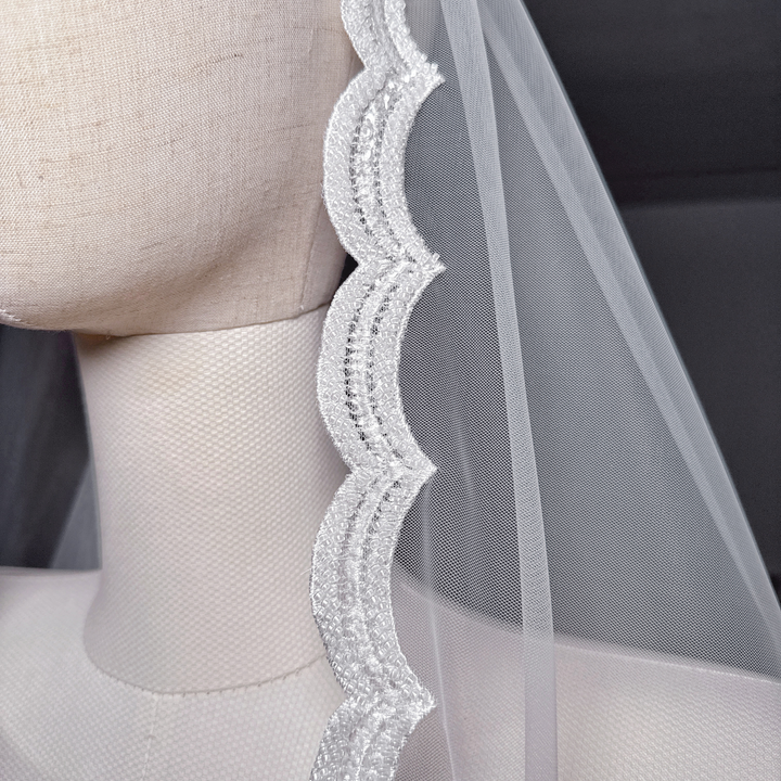 Close-up detail of the intricate beadwork and floral lace trim on a royal cathedral length beaded mantilla wedding veil.