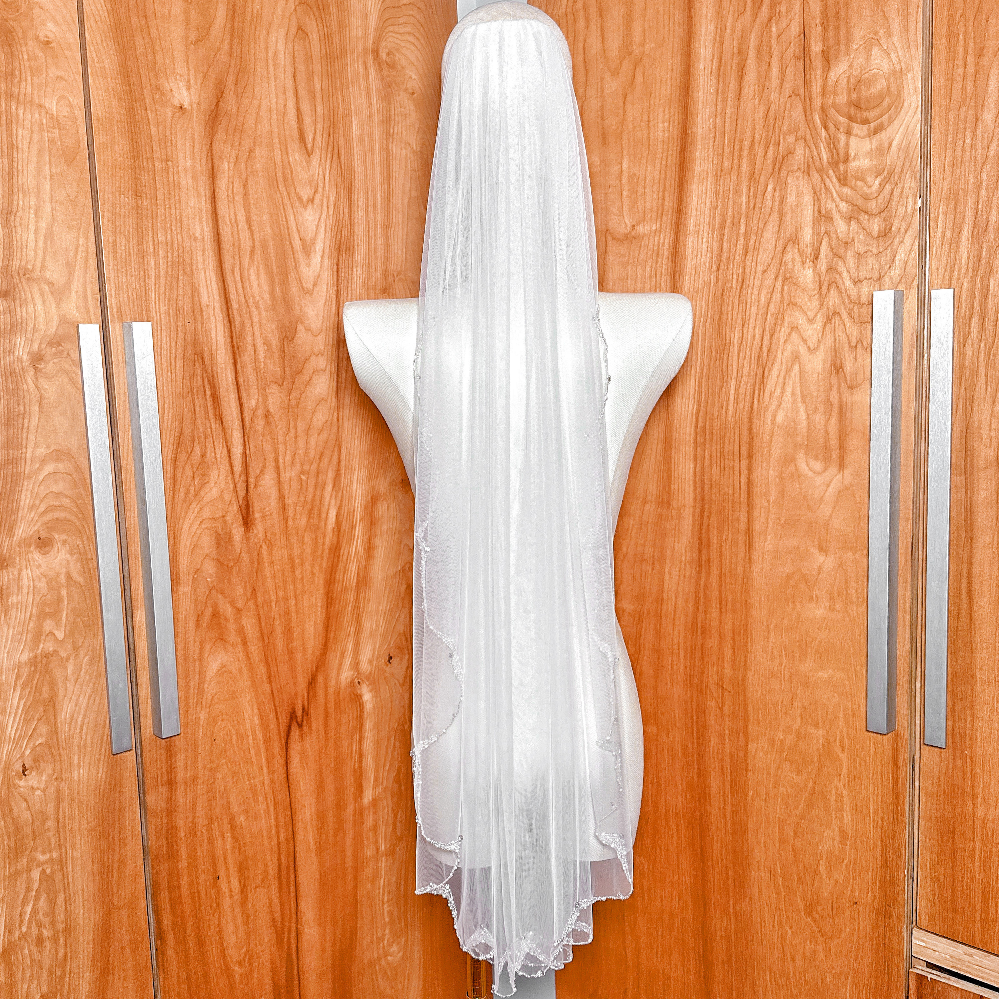Full-length view of a single-tier beaded pearl edge wedding veil in a versatile 40-inch fingertip length.