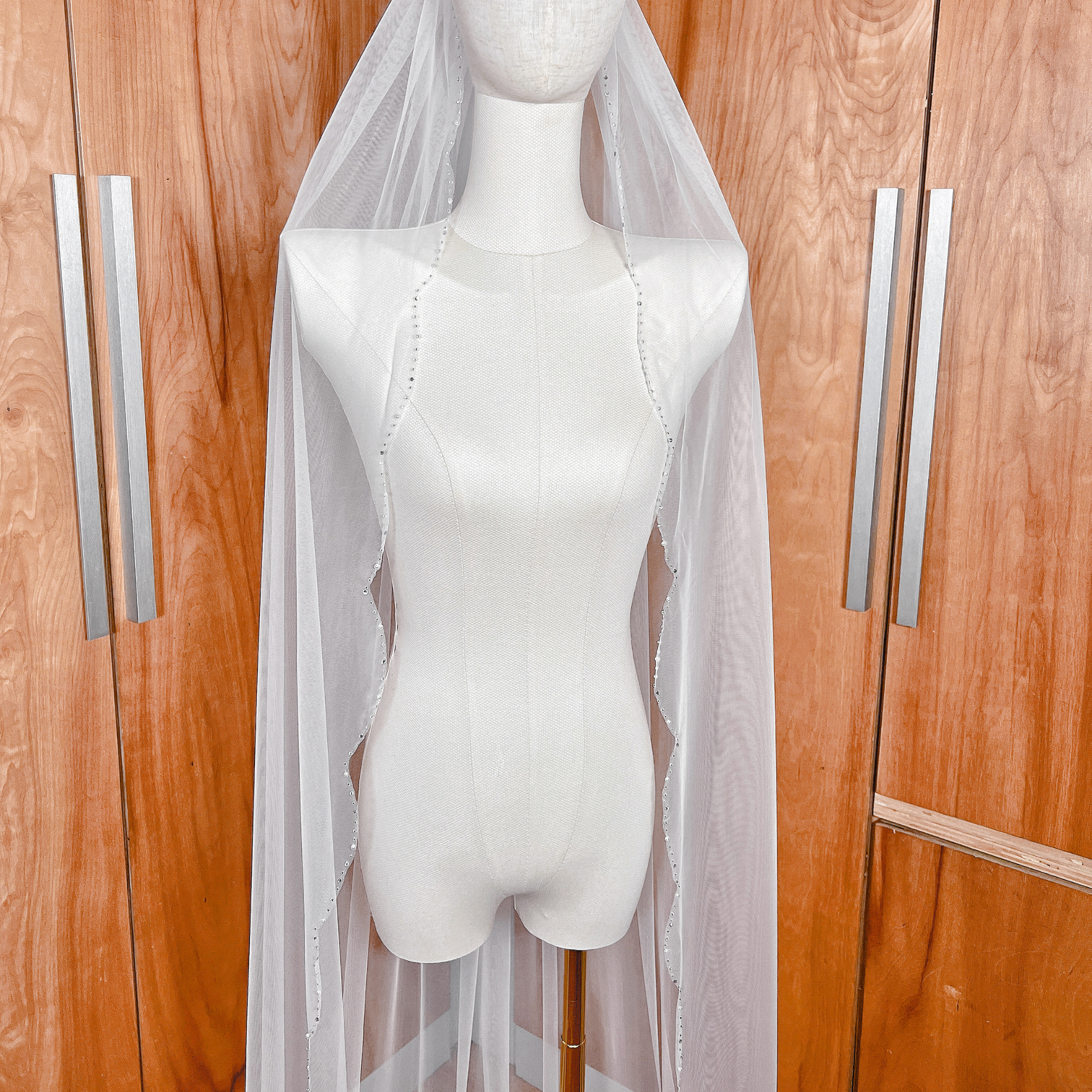 High-resolution detail of hand-sewn beads and crystals on a scalloped edge wedding veil.