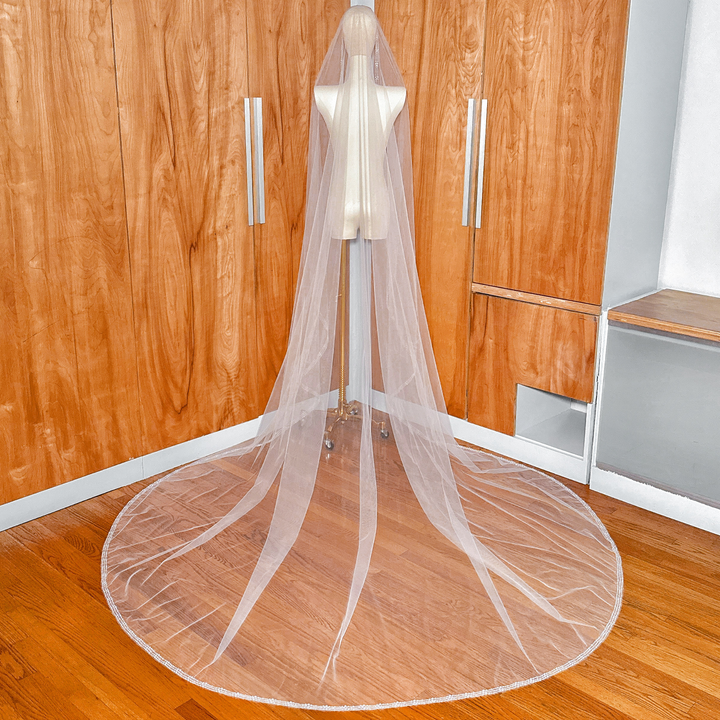 Full-length view of an intricately beaded cathedral veil with pearls and crystals on a mannequin.