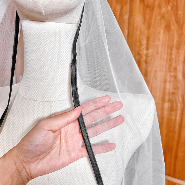 Close-up of the black satin trim edging on a cathedral length cascade wedding veil.