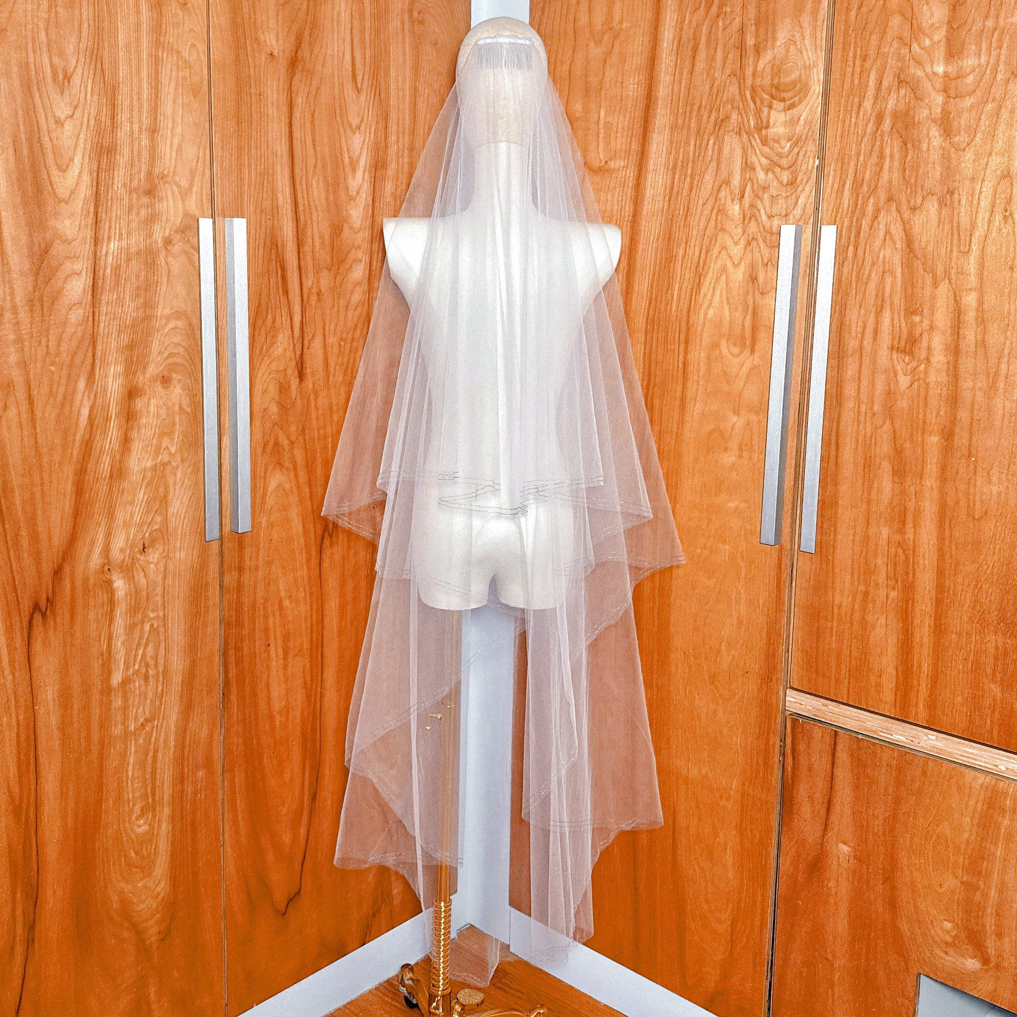 Back view of a waltz length two tier wedding veil featuring a shimmering blue metallic stitched edge.