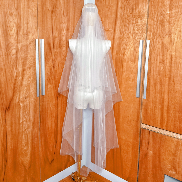 Back view of a waltz length two tier wedding veil featuring a shimmering blue metallic stitched edge.