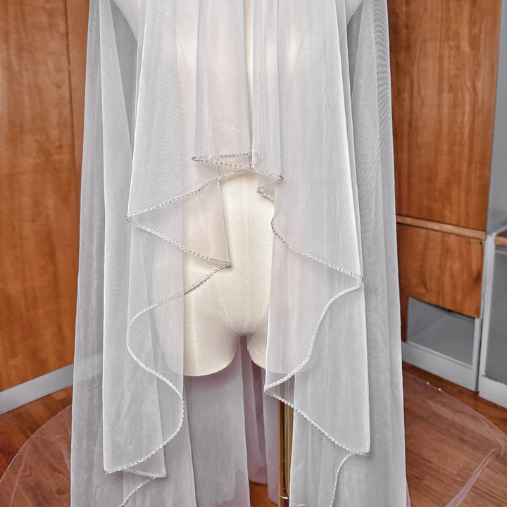 Detailed view of the top blusher layer on a two-tier cathedral length wedding veil featuring a delicate rhinestone edge.