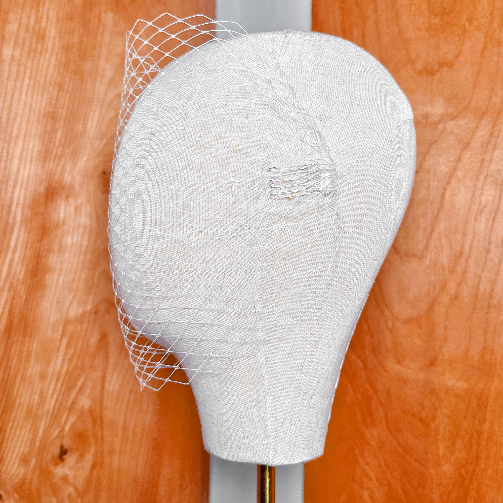 Side profile of a bridal bandeau birdcage wedding veil showing hair attachment clips.