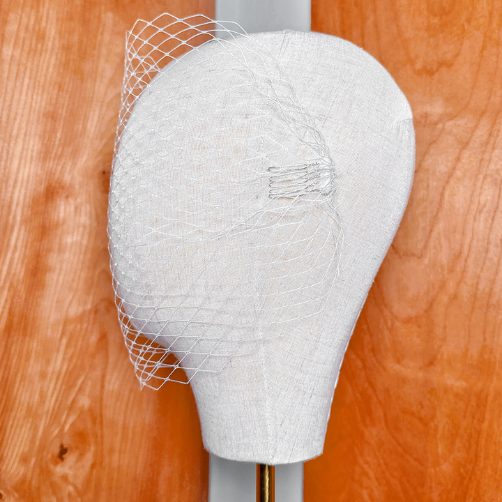 Side profile of a bridal bandeau birdcage wedding veil showing hair attachment clips.