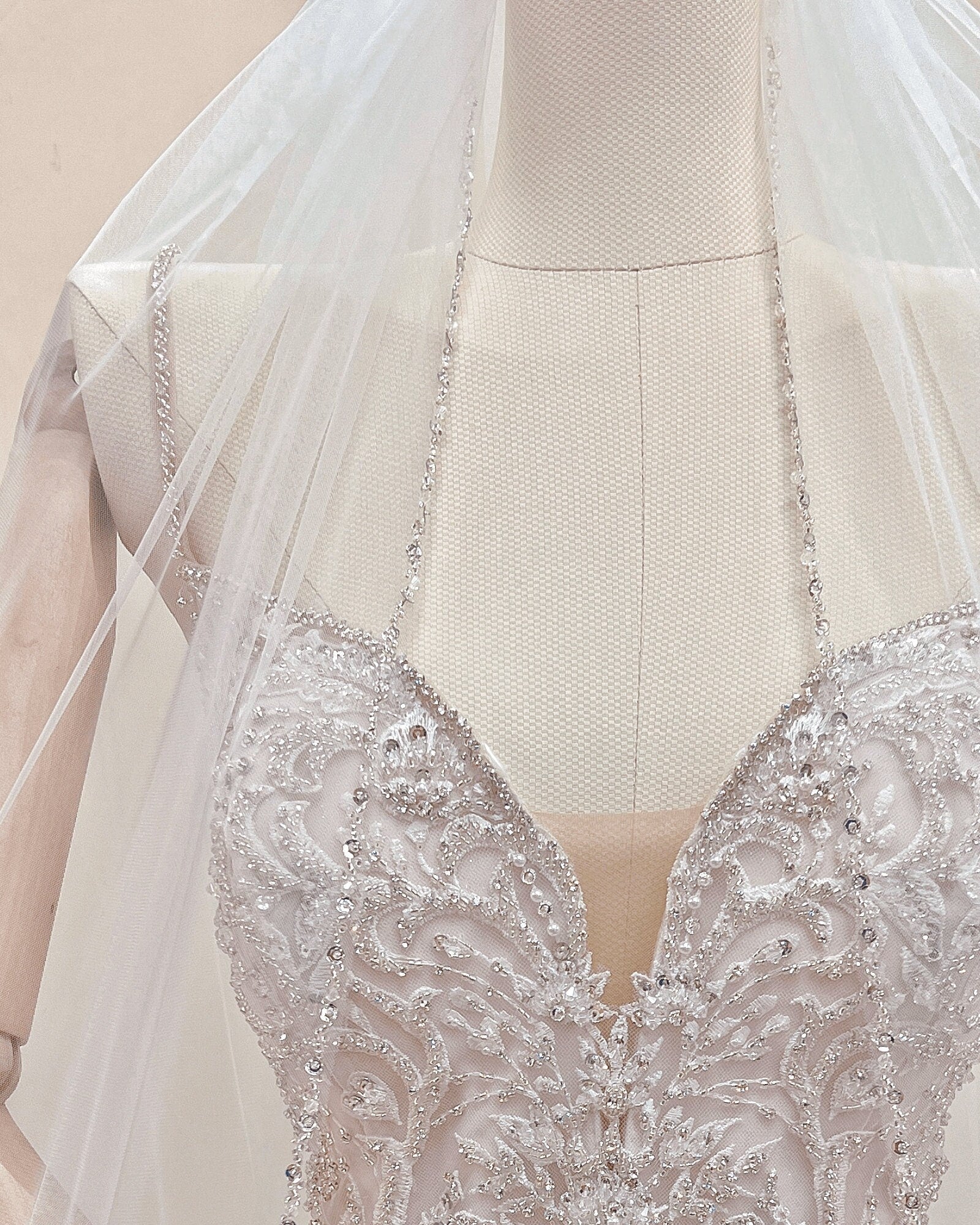 Sheer tulle fabric of a waltz length beaded edge wedding veil shown on a mannequin.