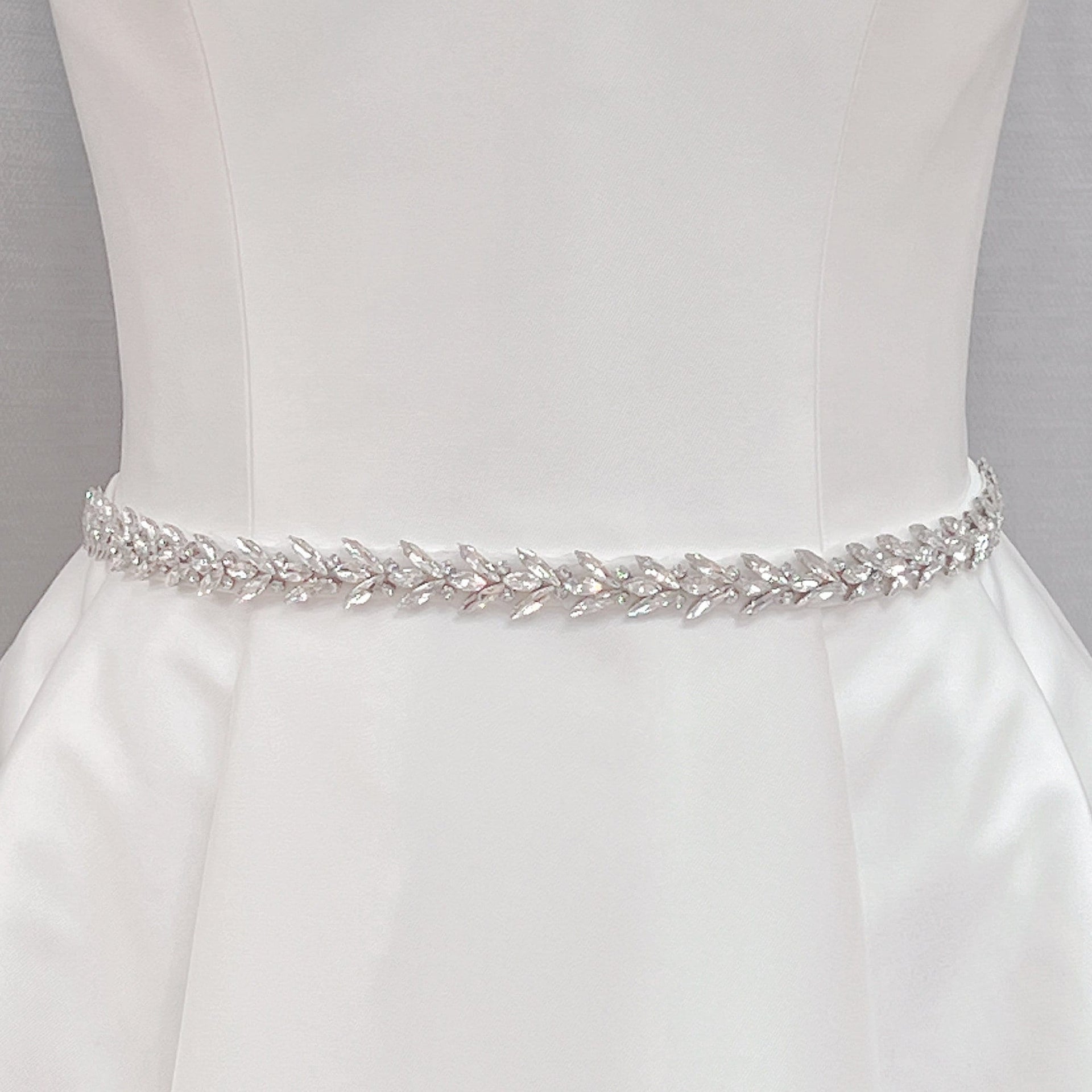 Elegant crystal rhinestone wedding dress sash and silver beaded bridal belt shown on a display mannequin.