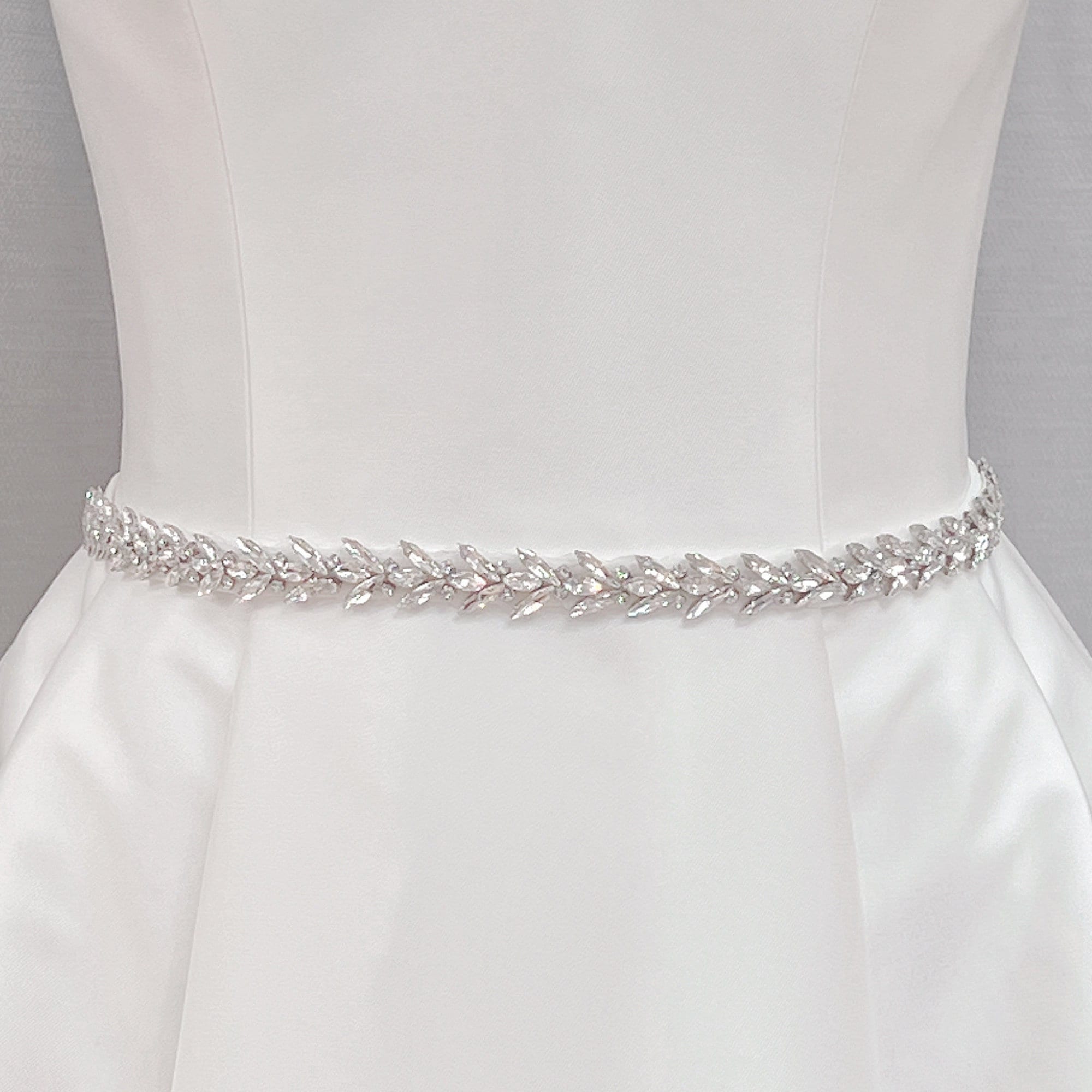 Elegant crystal rhinestone wedding dress sash and silver beaded bridal belt shown on a display mannequin.