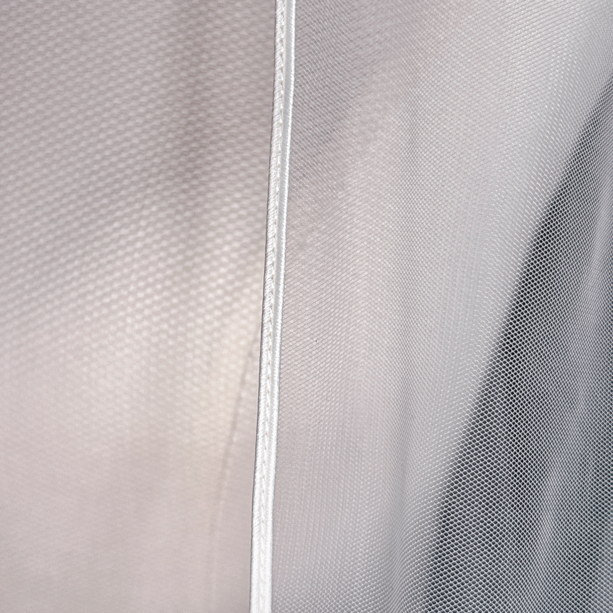 Clean border detail of a cathedral length cascade wedding veil draped elegantly against a neutral background.