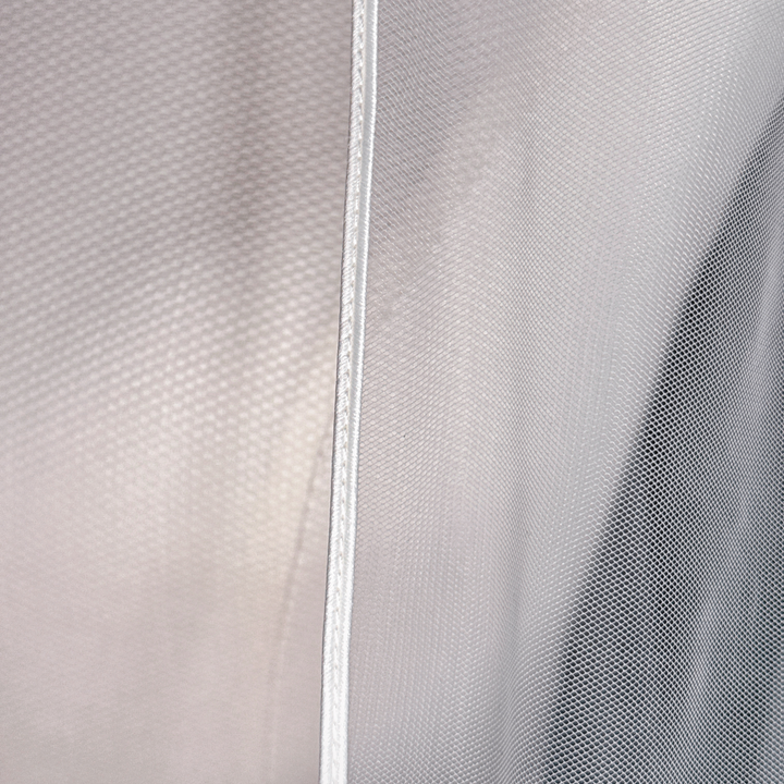 Clean border detail of a cathedral length cascade wedding veil draped elegantly against a neutral background.