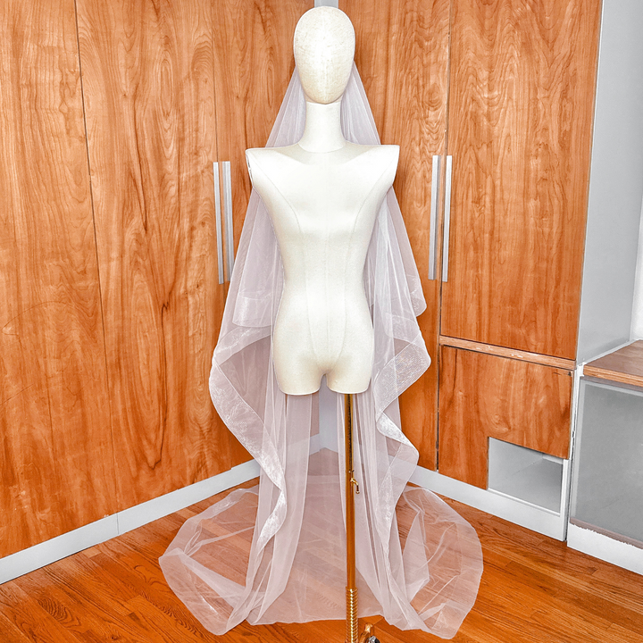 Elegant two tier wedding veil with 3 inch horsehair trim and blusher shown in cathedral length on a dress form.