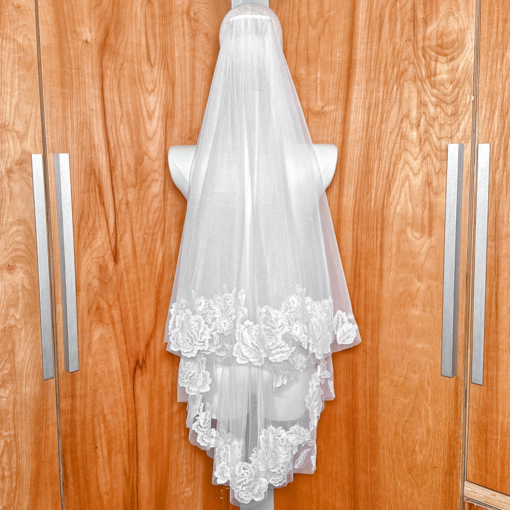 Back view of a bridal fingertip length two tier wedding veil featuring intricate floral lace.