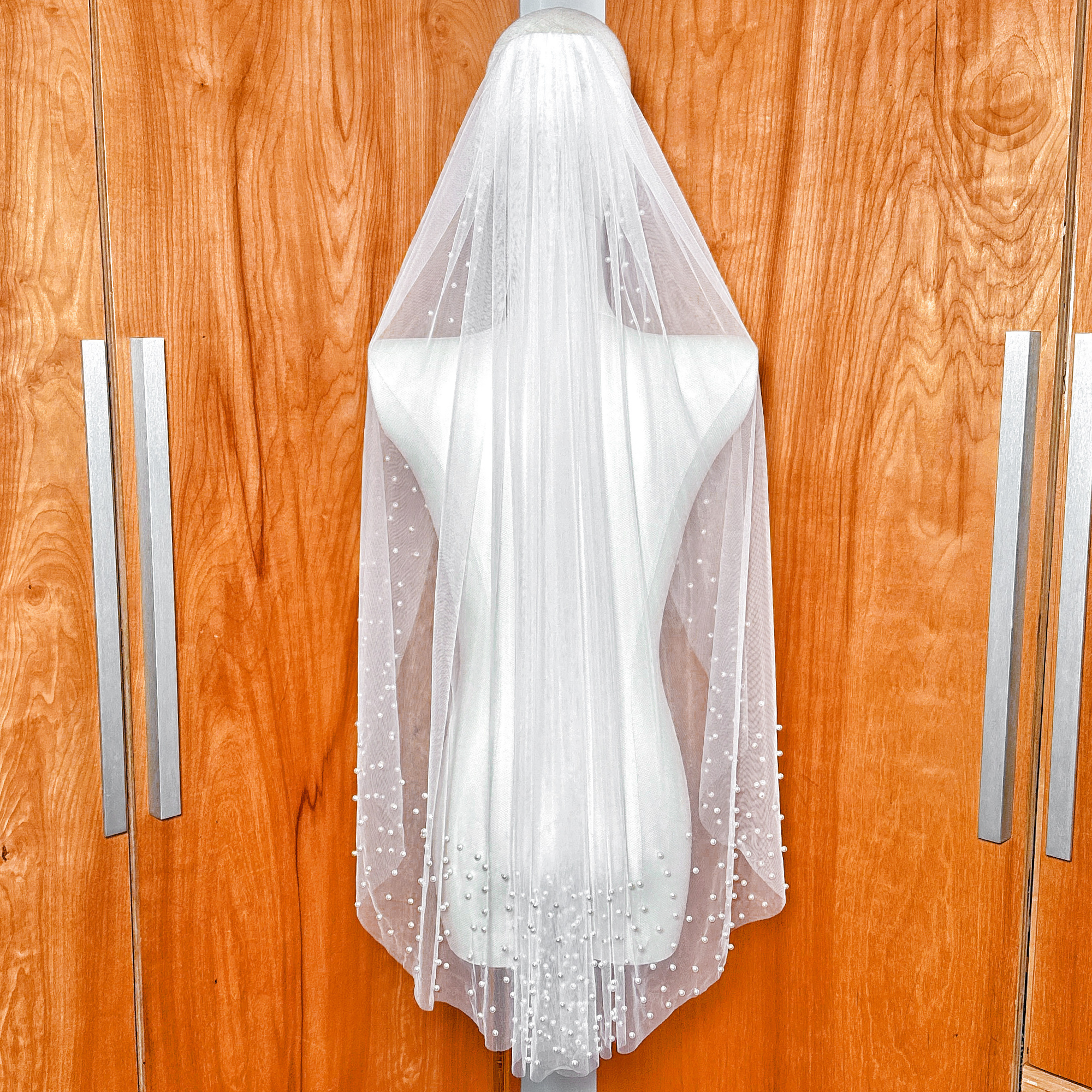 Rear view of a bridal fingertip veil with a scattered pearl edge, showcasing how the length falls perfectly at the fingertips.