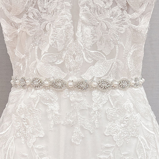 Close up view of a silver rhinestone and pearl bridal belt showcasing the sparkling gemstone pattern.