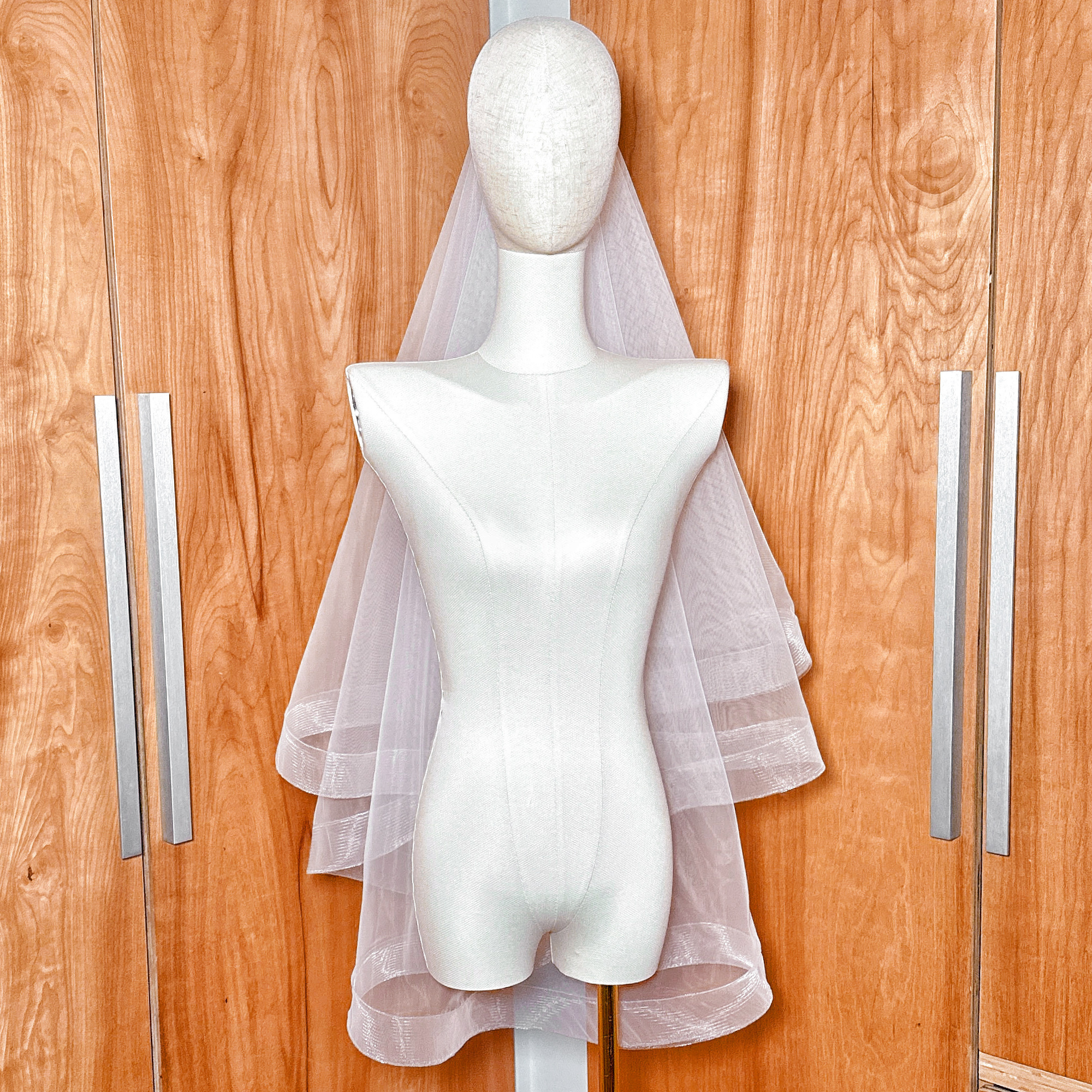 Two tier horsehair wedding veil with blusher and 2 inch edging in fingertip length, professionally displayed on a mannequin.