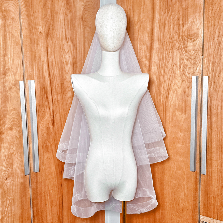 Two tier horsehair wedding veil with blusher and 2 inch edging in fingertip length, professionally displayed on a mannequin.