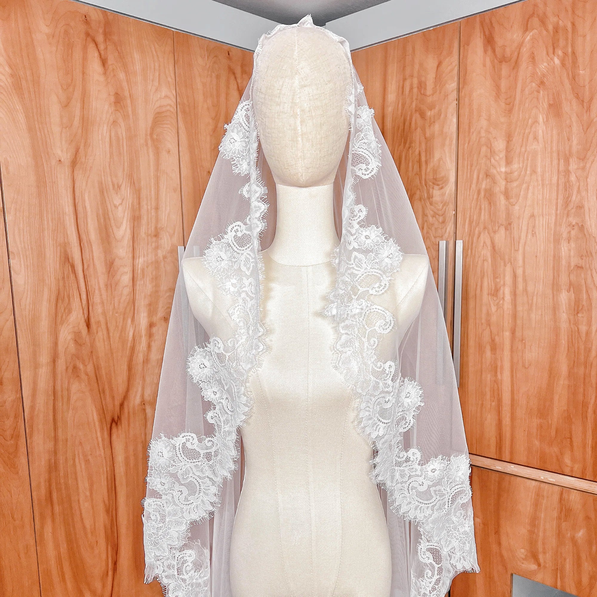 Close-up of the intricate scalloped Chantilly lace edge on a cathedral length bridal mantilla veil.