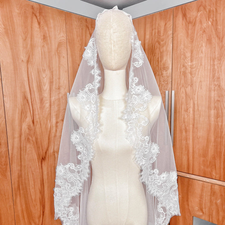 Close-up of the intricate scalloped Chantilly lace edge on a cathedral length bridal mantilla veil.