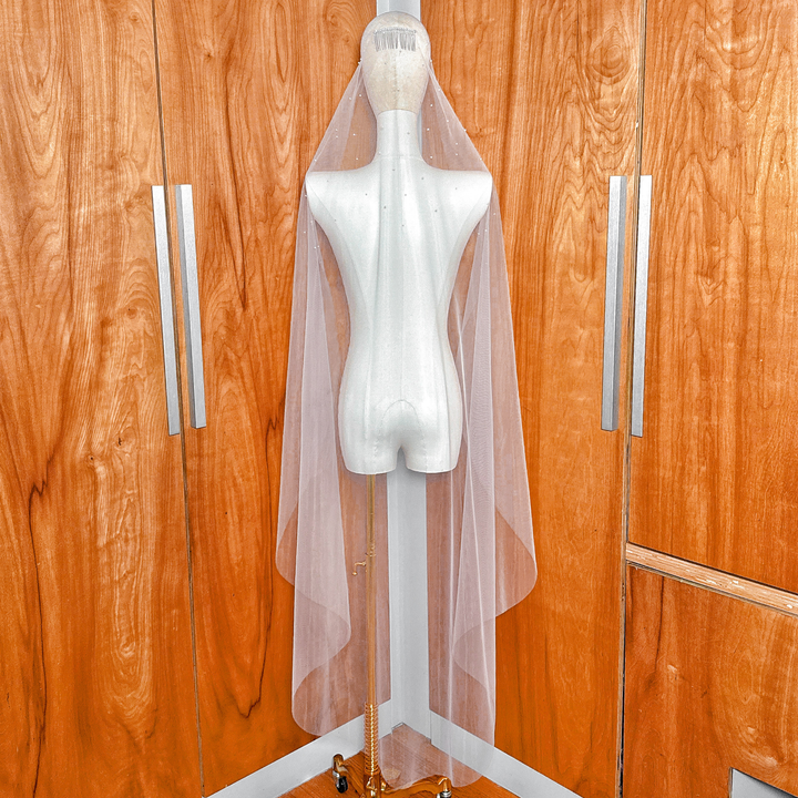 Full back view of a waltz length bridal veil with scattered pearls and a classic mantilla style framing the silhouette.