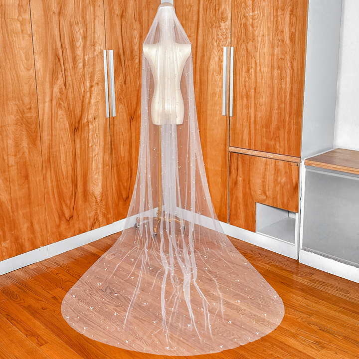 The wide train of a scattered pearl wedding veil in cathedral length, showing the density of pearls near the bottom edge.