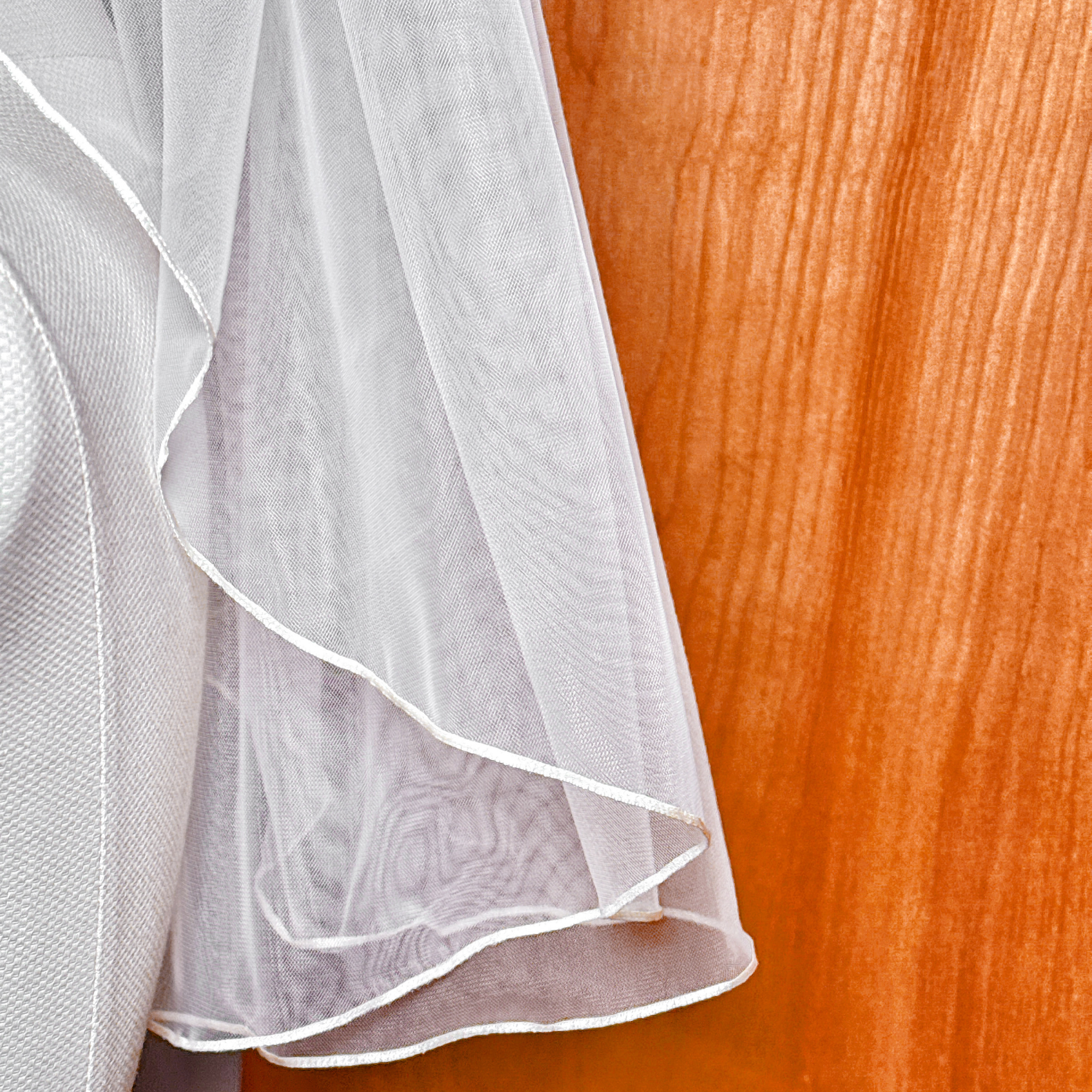 Close-up of a bridal shoulder length wedding veil featuring a delicate micro ribbon edge.