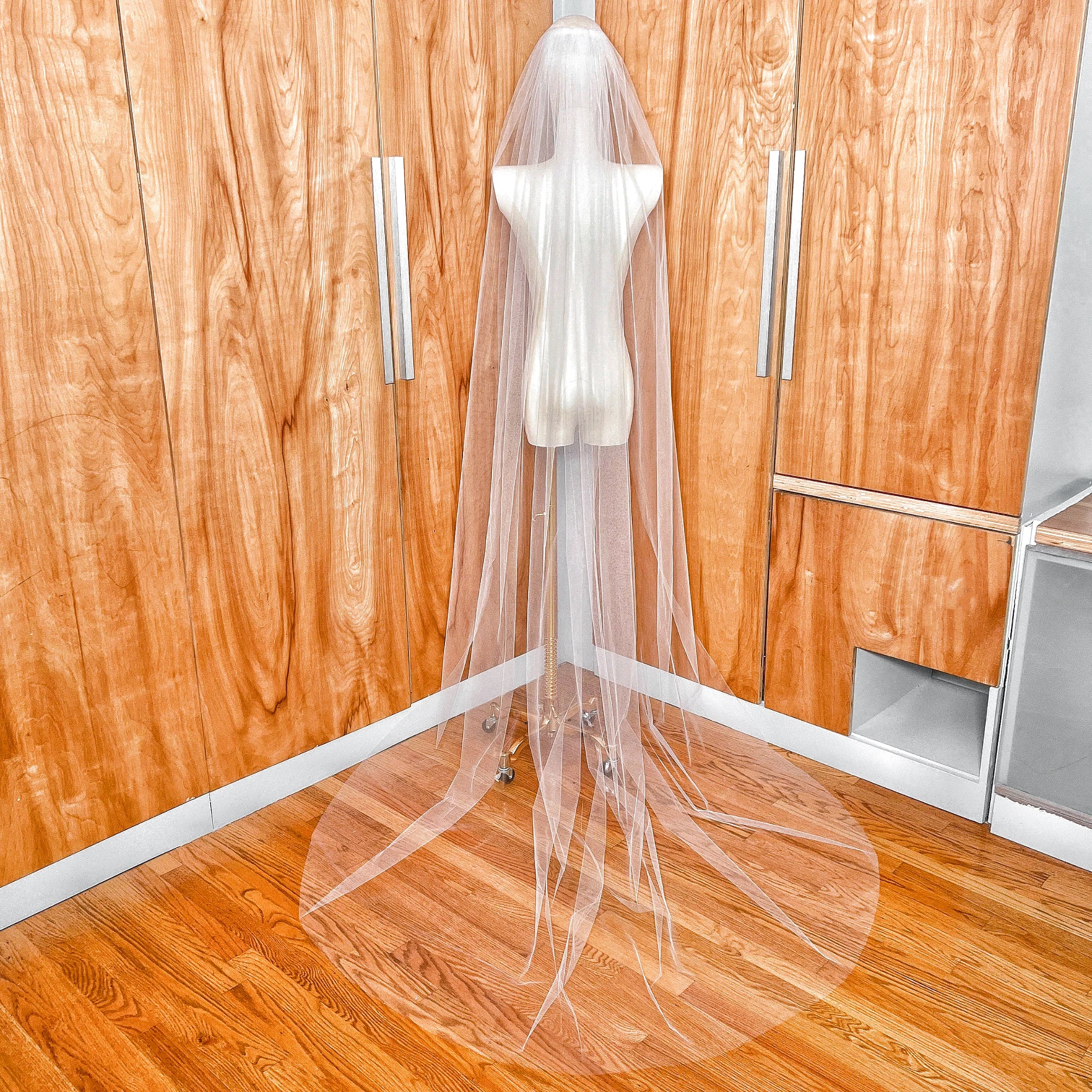 Rear view of a sheer single tier chapel length veil showing the airy flow and floor-length tulle drape.