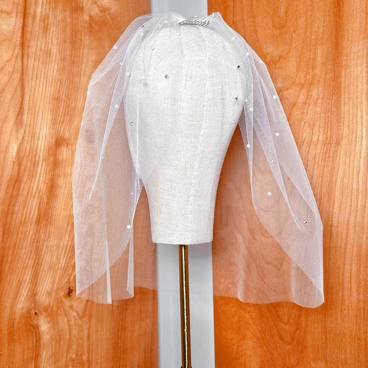 Detailed texture of the bridal tulle birdcage wedding veil highlighting the scattered rhinestones and pearls.
