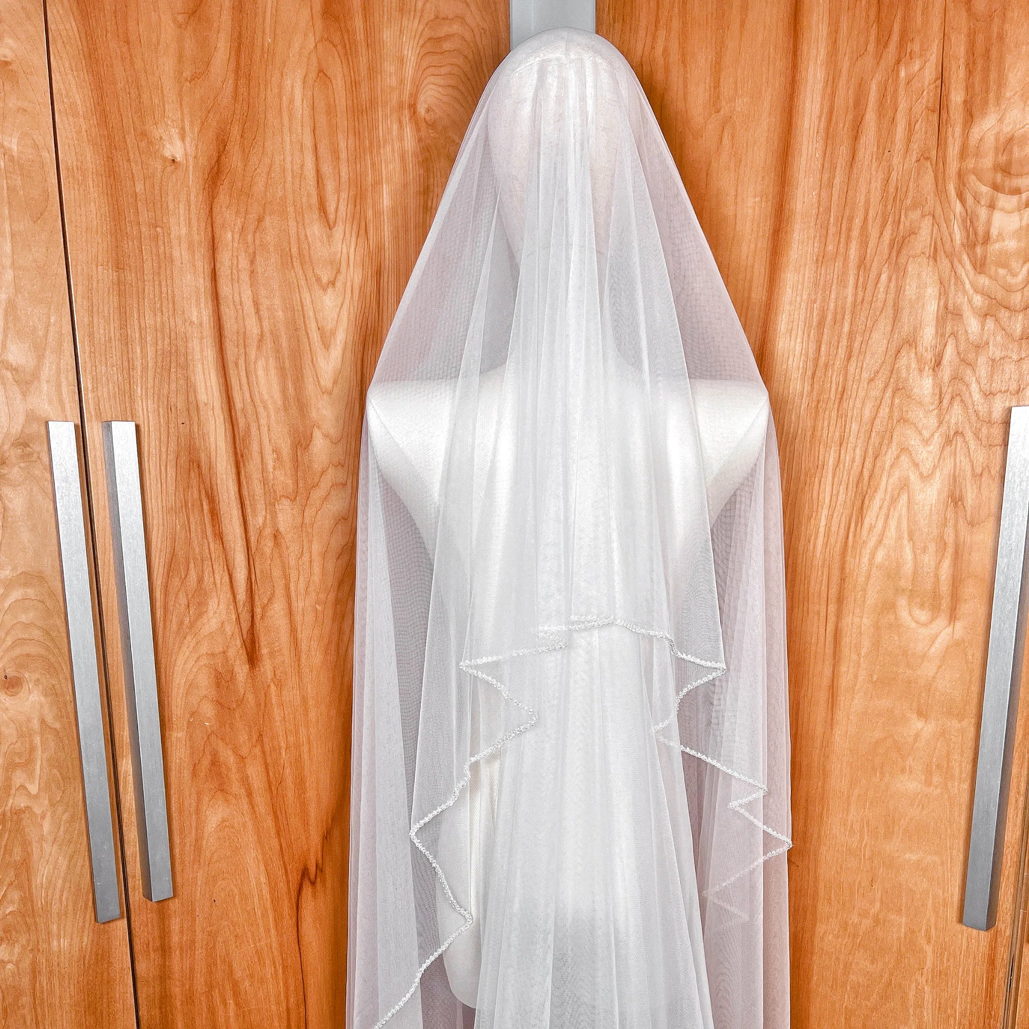Sheer bridal tulle texture of a cathedral length two tier crystal beaded edge wedding veil with blusher.