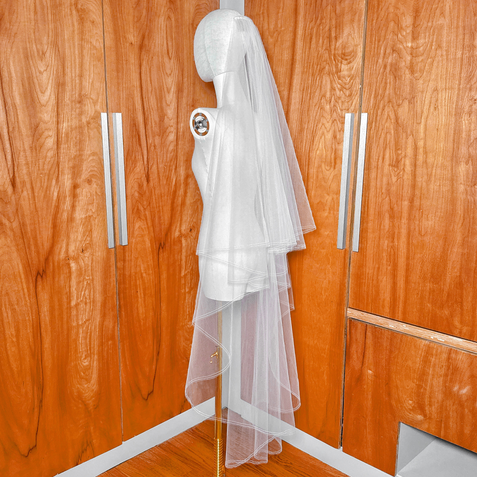 Sheer bridal tulle fabric of a waltz length two tier wedding veil with a pencil edge and blusher on a mannequin.